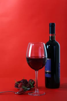 Red wine and glass with red background
