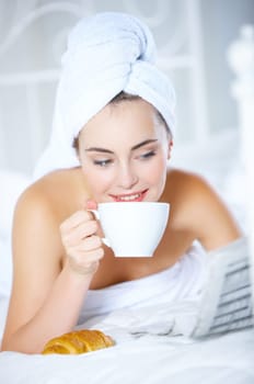 Portrait of cute teenage girl lying on white bed