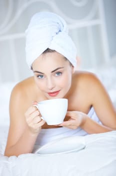 Portrait of cute teenage girl lying on white bed