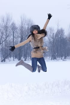 Young Jumping woman in snowy winter outdoors