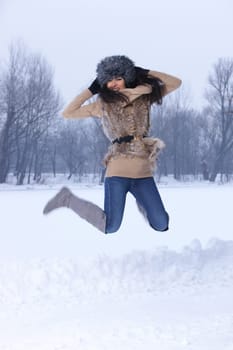 Young Jumping woman in snowy winter outdoors