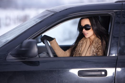 Beautiful woman in car in snowy winter outdoors