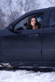 Beautiful woman in car in snowy winter outdoors