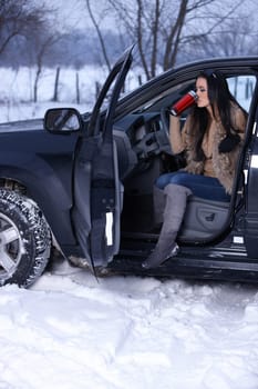 Beautiful woman in car in snowy winter outdoors