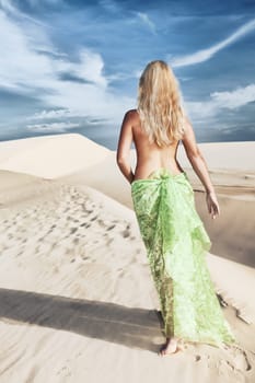Woman walking among desert dunes at day time