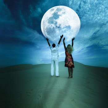 Romantic couple touching the Moon in desert