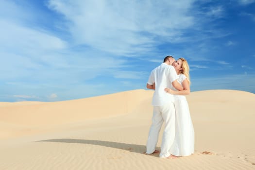 Young couple on desert dunes in white