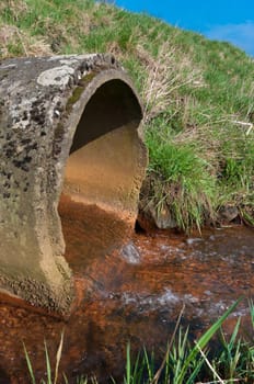 water flowing from a drain pipe into a small river