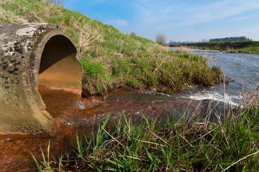 water flowing from a drain pipe into a small river