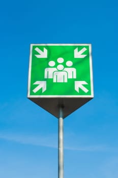 emergency assembly point green sign against a blue sky