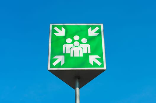 emergency assembly point green sign against a blue sky