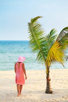 Woman in hat walking on the tropical beach