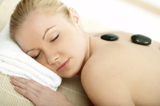 Young blond woman getting lastone treatment at spa