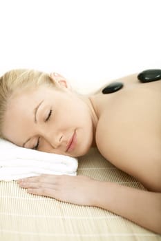 Young blond woman getting lastone treatment at spa