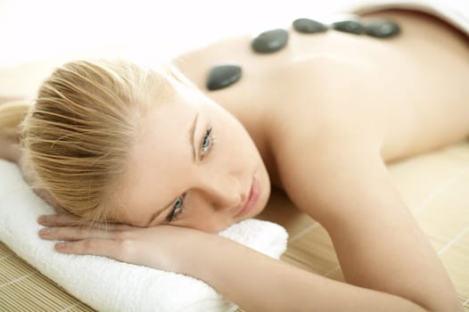 Young blond woman getting lastone treatment at spa