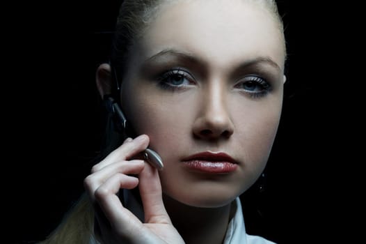 Beautiful business woman wearing black tie and white shirt isolated on black background talking via wireless headset