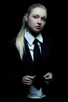 Beautiful business woman wearing black tie and jacket isolated on black background