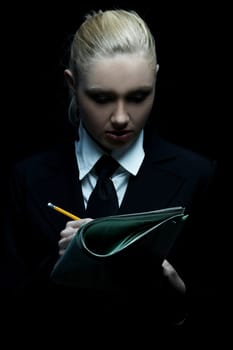 Beautiful business woman wearing black tie and jacket isolated on black background holding newspaper