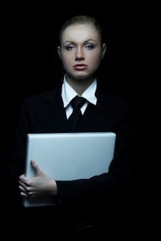 Beautiful business woman wearing black tie and jacket isolated on black background with laptop computer