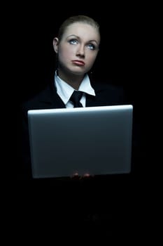 Beautiful business woman wearing black tie and jacket isolated on black background with laptop computer