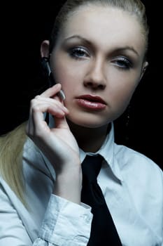 Beautiful business woman wearing black tie and white shirt isolated on black background talking via wireless headset