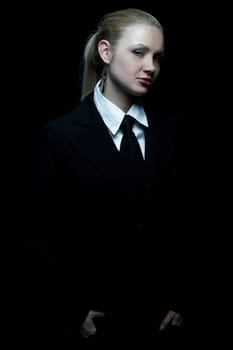 Beautiful business woman wearing black tie and jacket isolated on black background