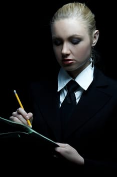 Beautiful business woman wearing black tie and jacket isolated on black background holding newspaper