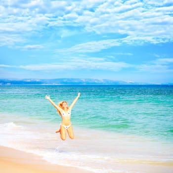 Young woman in bikini  jumping on the tropical beach