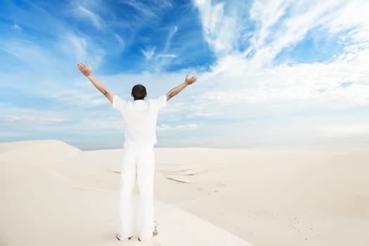Rear view of man with hands up in desert