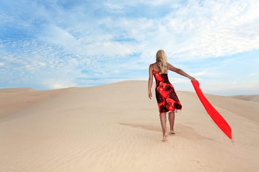 Young woman with red scafr walking alone in desert