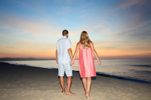 Couple walking on the beach at sunrise time.