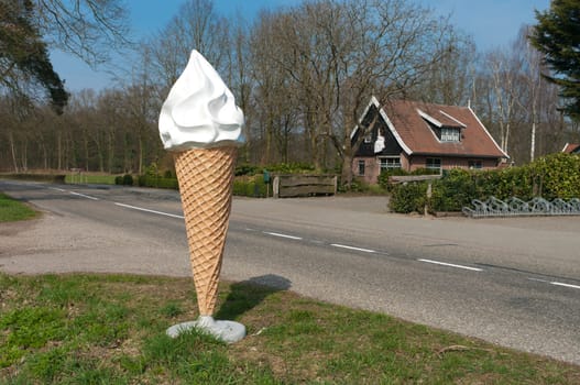 large ice cream cone statue at the side of the road to attract people