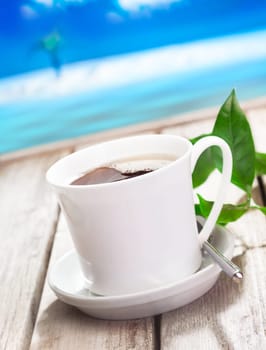 Refreshing cup of coffee served against a blue tropical coastline on a summer vacation