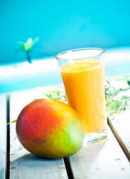 Creamy mango smoothie with blended fresh mango juice and yoghurt served overlooking a tropical ocean