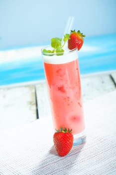 Scrumptious chilled glass of yoghurt and strawberry smoothie served on a deck overlooking the sea
