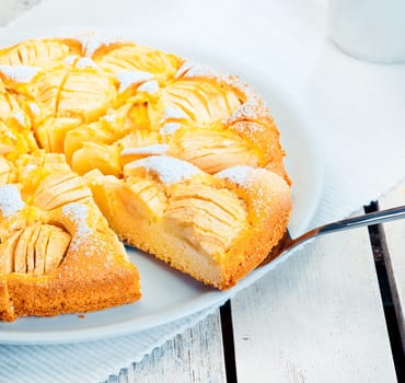 Closeup on a spatula inserted under a slice of freshly baked apple tart ready for serving