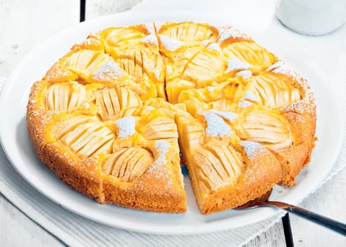 High angle view of a sliced freshly baked apple tart ready for serving on a white plate