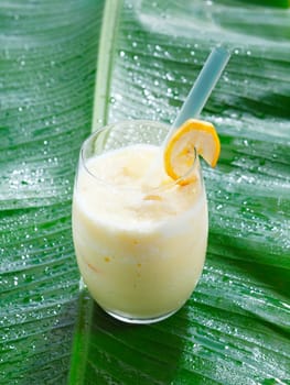 High angle view of a single glass of chilled banana smoothie or blended cocktail served on a banana frond with copyspace