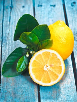 Freshly cut half and whole lemons with leaves on rustic boards