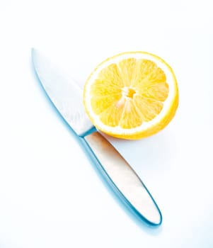 Halved fresh lemon for garnishing with a knife on a white studio bacjground