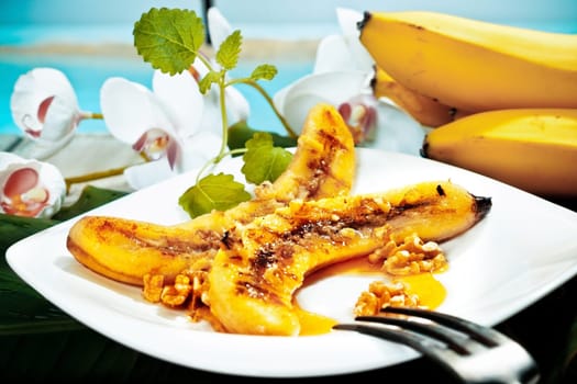 Delicious golden brown grilled banana and walnut dessert served on a white platter