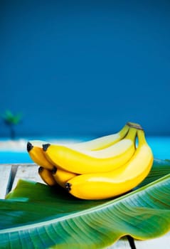 Bunch of ripe tropical bananas on a banana leaf with ocean backdrop