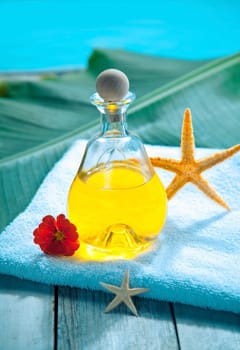 Bottle of golden essential oil plant extract on a towel alongside a pool ready for an aromatherapy spa treatment