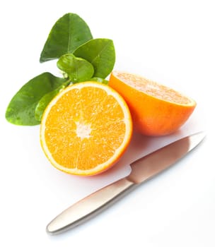 Fresh halved orange with citrus leaves and a knife on a white studio background