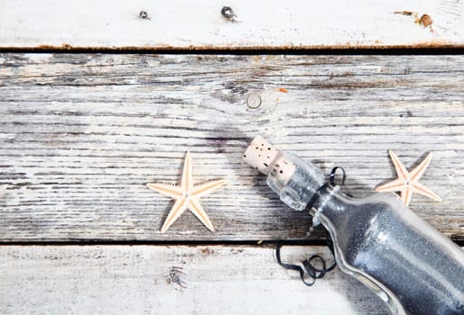 Nautical background with starfish and a clear glass corked bottle on weathered timber planks with woodgrain