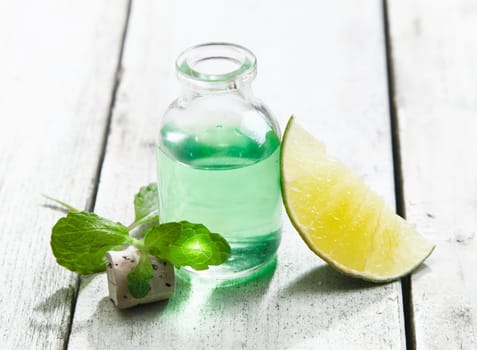 Cool and refreshing mint essential oil in a clear glass bottle with lemon for a rejuvenating spa treatment