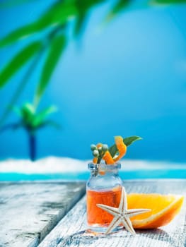 A small glass bottle of orange essential oil plant extract standing on a wooden seaside deck ready for a tropical spa treatment