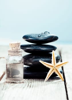 Balanced column of smooth black spa massage stones with a bottle of essential oil ready for a luxurious hot rock massage