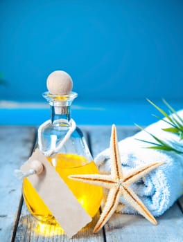 Marine aromatherapy spa treatment with a decanter of golden essential oil and a starfish on a deck overlooking the sea