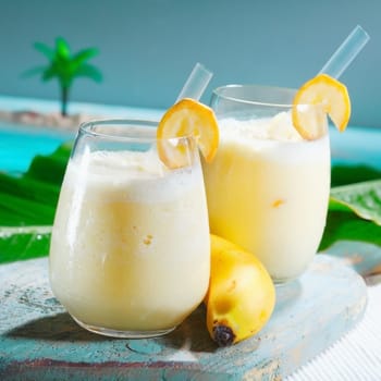 Closeup of two glasses of healthy fruity banana smoothie blended with yoghurt served at a seafront tropical resort